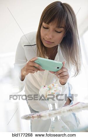 Mixed race woman photographing dessert View Large Photo Image Stock Photo - Mixed race woman photographing dessert. Fotosearch