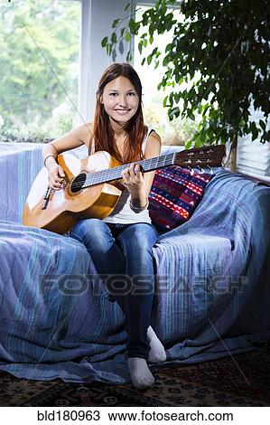 Mixed race woman playing guitar on sofa View Large Photo Image Stock Image - Mixed race woman playing guitar on sofa. Fotosearch