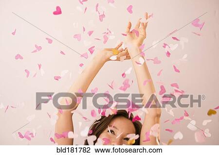 Stock Image - Mixed race woman playing in confetti. Fotosearch
