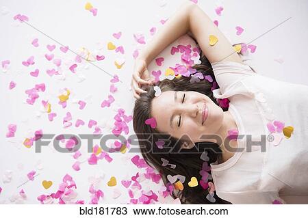 Stock Image - Mixed race woman playing in confetti. Fotosearch