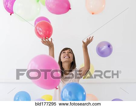 Stock Photography - Mixed race woman playing with balloons. Fotosearch