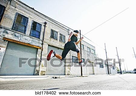 Stock Image - Mixed race woman running outdoors. Fotosearch