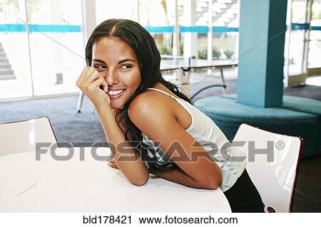 Stock Image - Mixed race woman sitting at table. Fotosearch