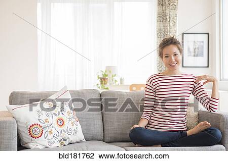 Stock Image - Mixed race woman sitting on sofa. Fotosearch