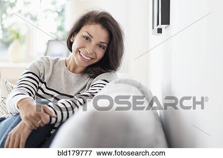 Mixed race woman sitting on sofa View Large Photo Image Stock Photo - Mixed race woman sitting on sofa. Fotosearch