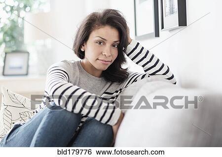 Mixed race woman sitting on sofa View Large Photo Image Stock Photograph - Mixed race woman sitting on sofa. Fotosearch