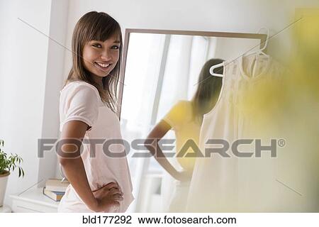 Stock Image - Mixed race woman smiling in front of mirror. Fotosearch