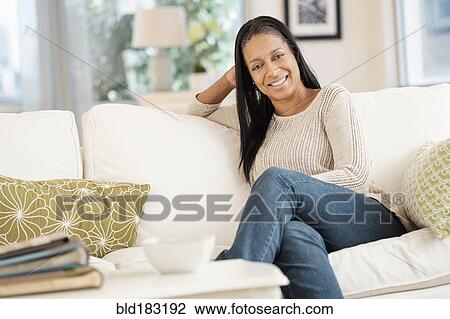 Mixed race woman smiling on sofa View Large Photo Image Stock Image - Mixed race woman smiling on sofa. Fotosearch