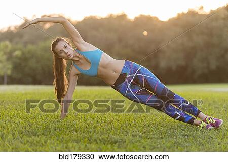 Stock Image - Mixed race woman stretching in field. Fotosearch