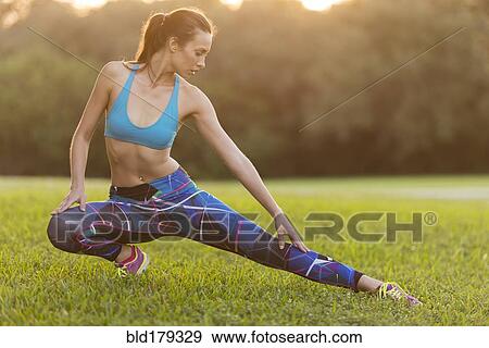 Stock Photo - Mixed race woman stretching in field. Fotosearch