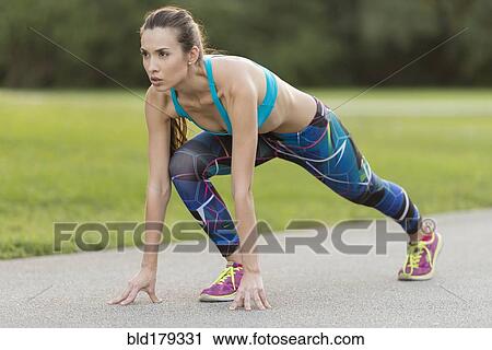 Stock Image - Mixed race woman stretching on road. Fotosearch