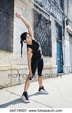 Stock Photo - Mixed race woman stretching on sidewalk. Fotosearch