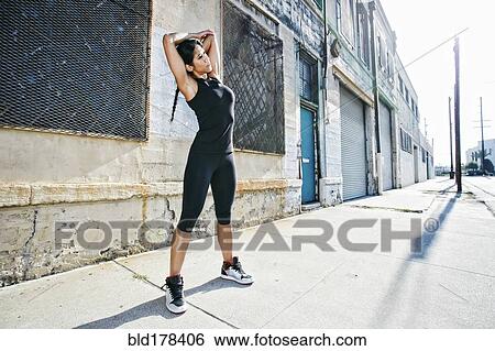 Stock Photograph - Mixed race woman stretching on sidewalk. Fotosearch