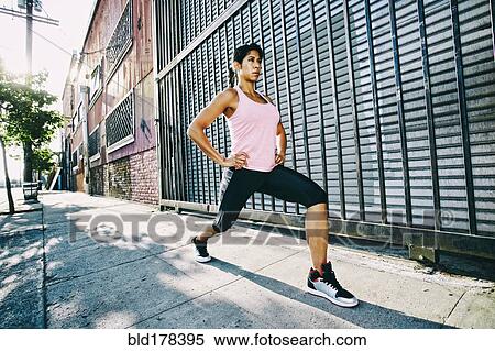 Stock Photography - Mixed race woman stretching on sidewalk. Fotosearch