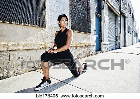 Stock Photography - Mixed race woman stretching on sidewalk. Fotosearch