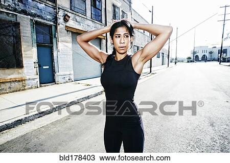 Stock Image - Mixed race woman stretching outdoors. Fotosearch