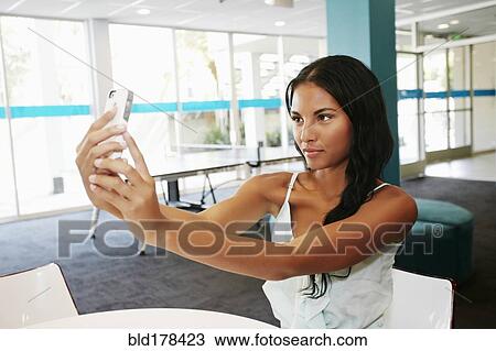 Mixed race woman taking selfie at table View Large Photo Image Stock Image - Mixed race woman taking selfie at table. Fotosearch