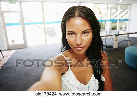 Picture - Mixed race woman taking selfie. Fotosearch