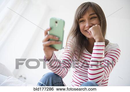 Stock Photograph - Mixed race woman taking selfie with cell phone. Fotosearch