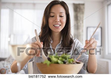 Stock Image - Mixed race woman tossing salad. Fotosearch