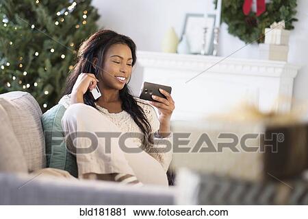 Mixed race woman using cell phone on sofa View Large Photo Image Stock Image - Mixed race woman using cell phone on sofa. Fotosearch