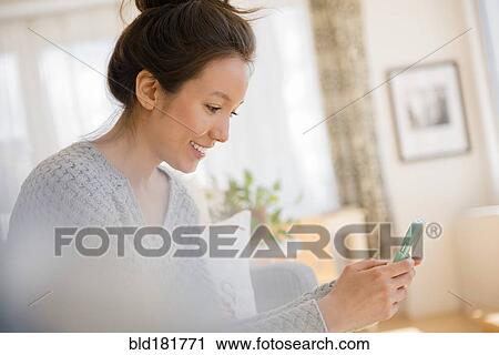 Stock Image - Mixed race woman using cell phone. Fotosearch