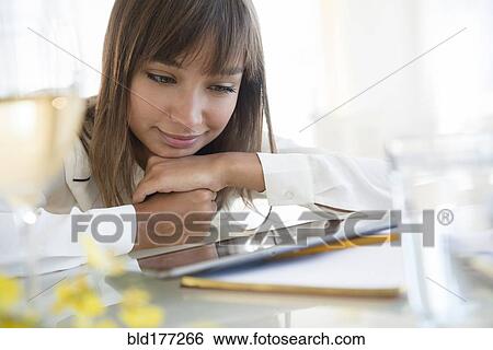 Stock Photograph - Mixed race woman using digital tablet. Fotosearch