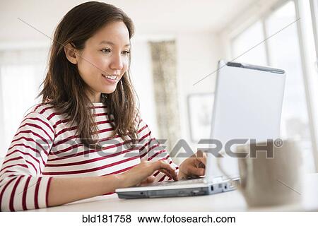 Stock Photo - Mixed race woman using laptop. Fotosearch
