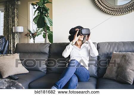 Stock Image - Mixed race woman using virtual reality goggles. Fotosearch