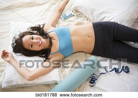 Stock Photo - Mixed race woman with workout gear on bed. Fotosearch