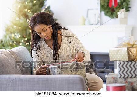 Picture - Mixed race woman wrapping Christmas gifts. Fotosearch