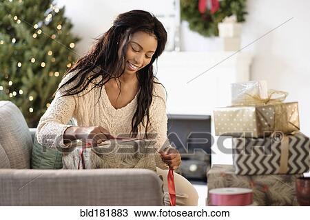 Stock Image - Mixed race woman wrapping Christmas gifts. Fotosearch
