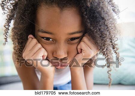 Stock Photography - Moody mixed race girl resting chin in hand. Fotosearch