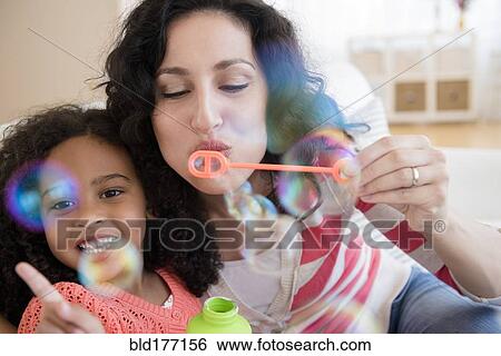 Stock Photograph - Mother and daughter blowing bubbles. Fotosearch