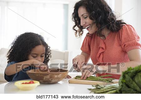 Stock Image - Mother and daughter chopping vegetables. Fotosearch