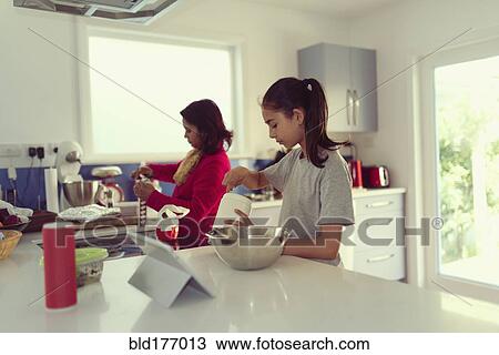 Stock Image - Mother and daughter cooking in kitchen. Fotosearch