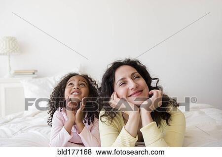 Stock Photo - Mother and daughter daydreaming on bed. Fotosearch