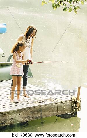 Stock Image - Mother and daughter fishing in lake. Fotosearch