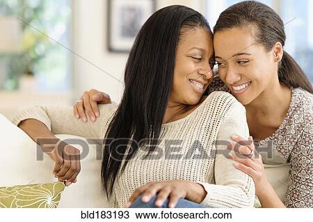 Mother and daughter hugging in living room View Large Photo Image Stock Image - Mother and daughter hugging in living room. Fotosearch