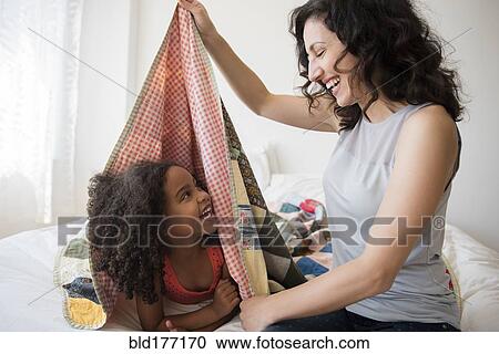 Stock Image - Mother and daughter playing in blanket fort. Fotosearch
