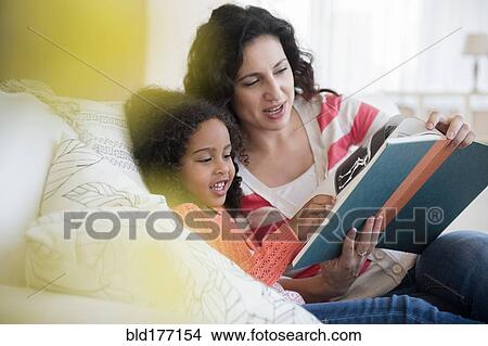 Picture - Mother and daughter reading on sofa. Fotosearch