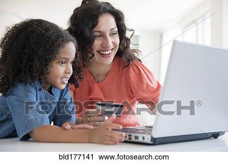 Stock Image - Mother and daughter shopping online. Fotosearch