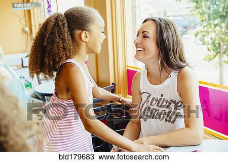 Mother and daughter smiling in cafe View Large Photo Image Stock Image - Mother and daughter smiling in cafe. Fotosearch