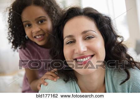 Stock Image - Mother and daughter smiling indoors. Fotosearch