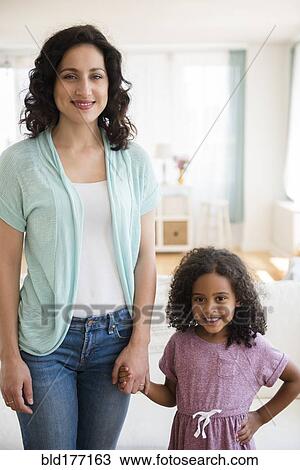 Stock Image - Mother and daughter smiling indoors. Fotosearch
