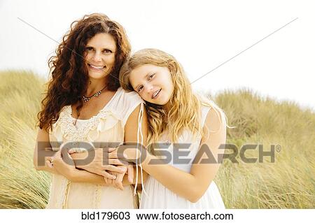 Stock Image - Mother and daughter smiling on beach. Fotosearch