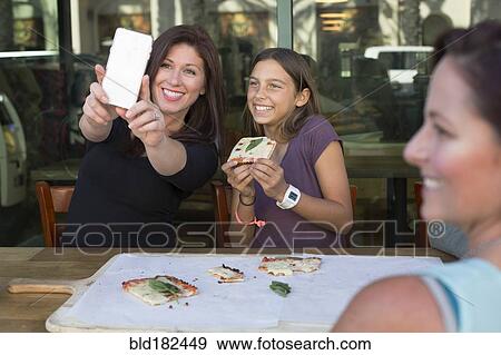 Stock Photo - Mother and daughter taking selfie in cafe. Fotosearch
