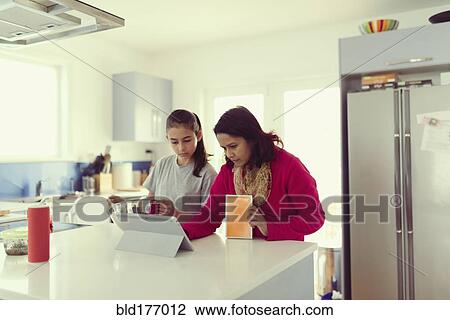 Mother and daughter using digital tablet in kitchen View Large Photo Image Stock Image - Mother and daughter using digital tablet in kitchen. Fotosearch