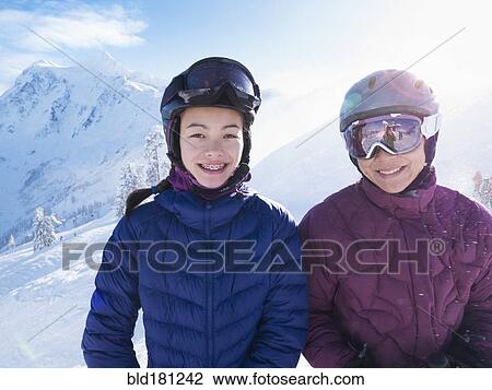 Stock Image - Mother and daughter wearing ski gear on snowy mountain. Fotosearch