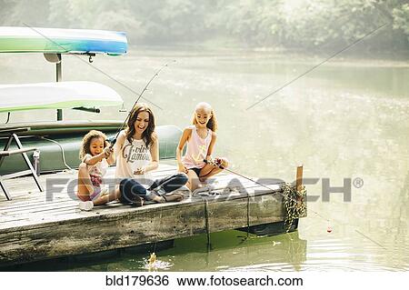 Stock Photograph - Mother and daughters fishing in lake. Fotosearch